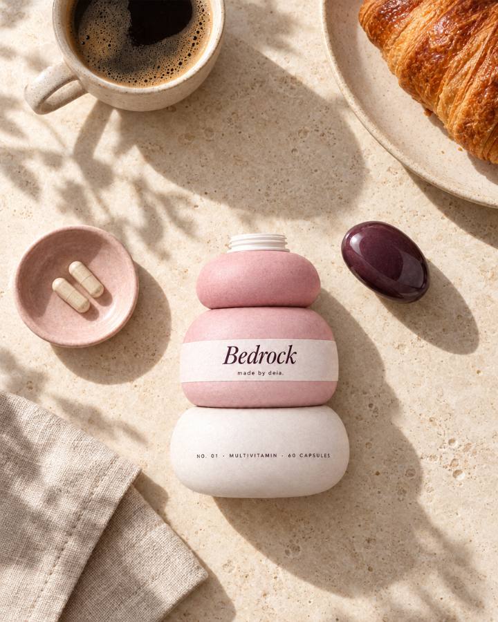 Bedrock with its top stone lifted, beside coffee, a croissant and two capsules